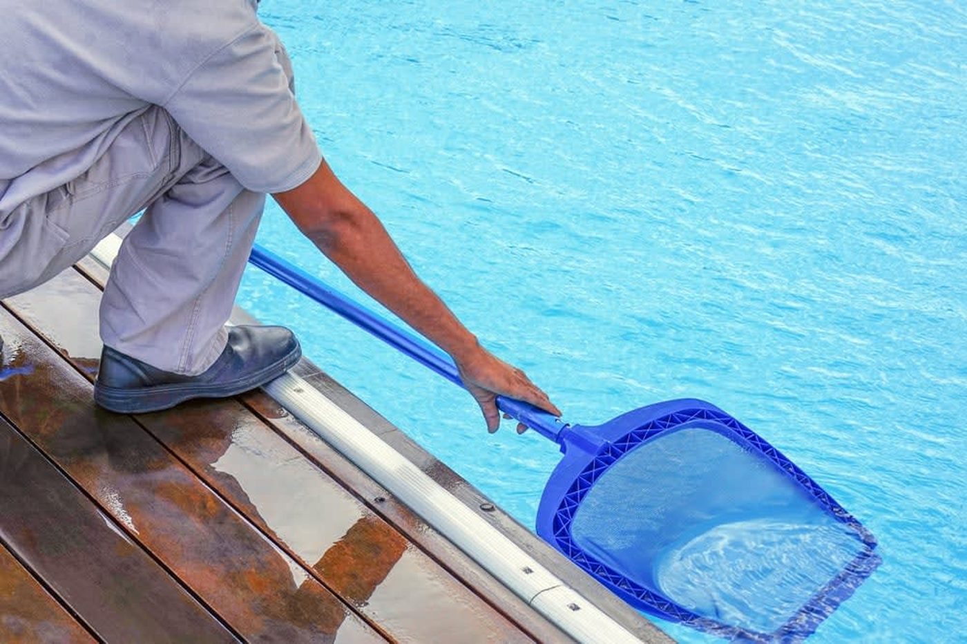 Pool service technician cleaning a swimming pool
